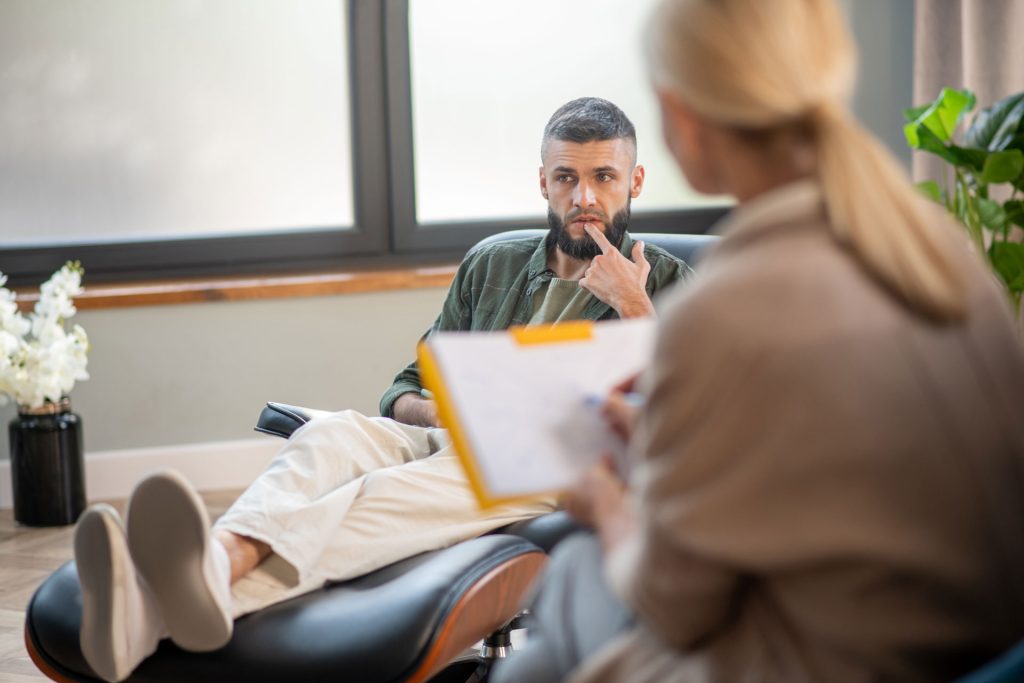 Man sitting on a chair sharing his thoughts with a therapist.