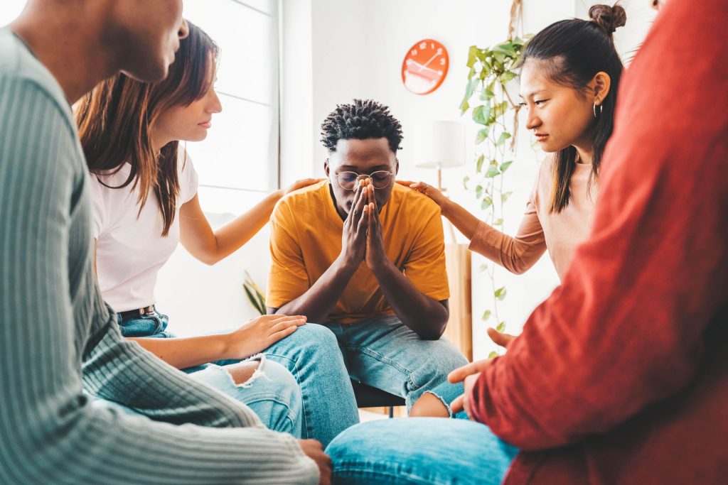 A group of friends giving comfort to their sad friend.