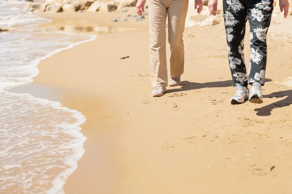 two unrecognizable person walking at the beach.
