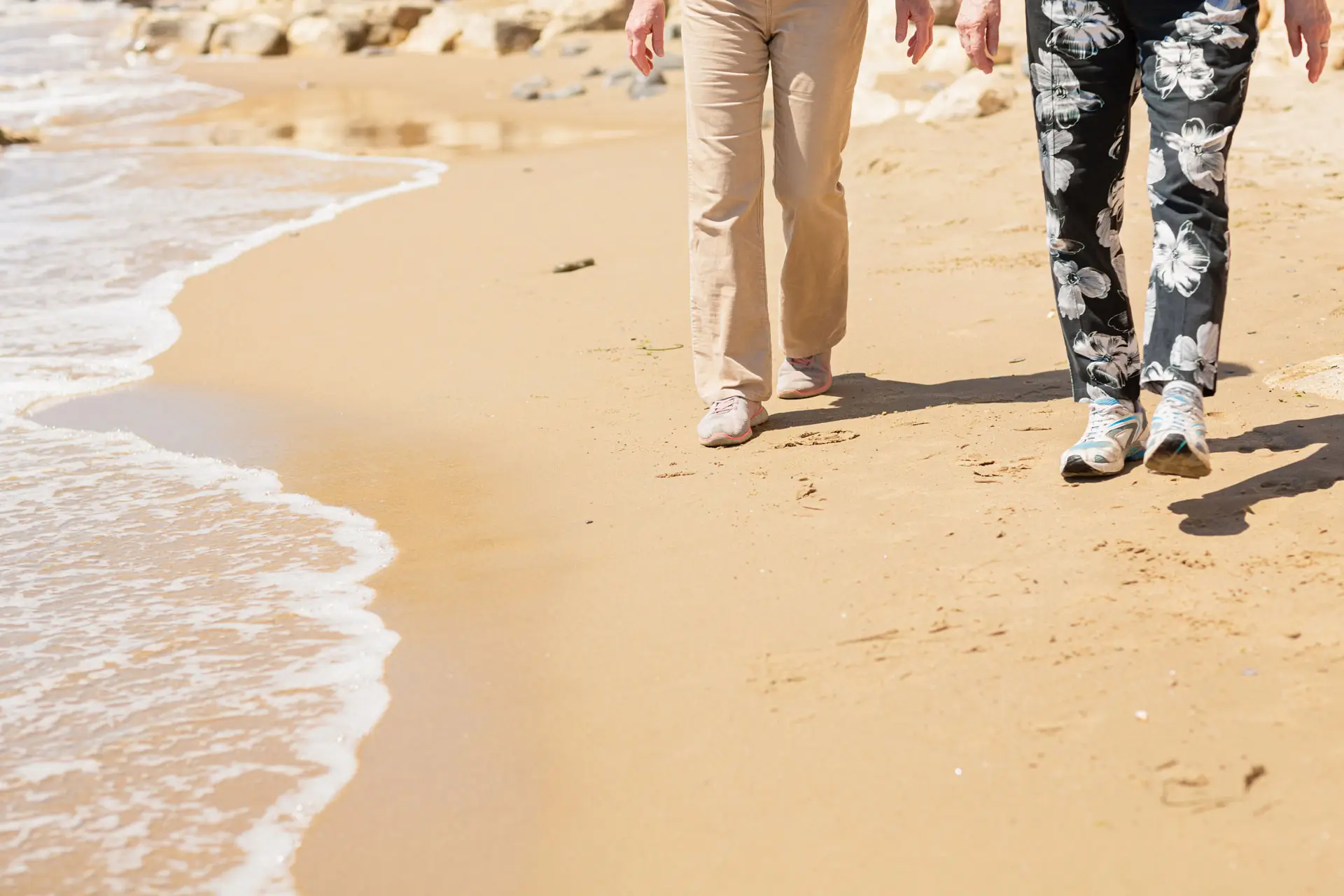 two unrecognizable person walking at the beach.