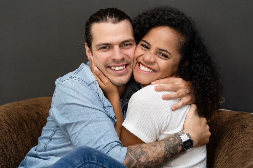 Hugging couple looking at camera.