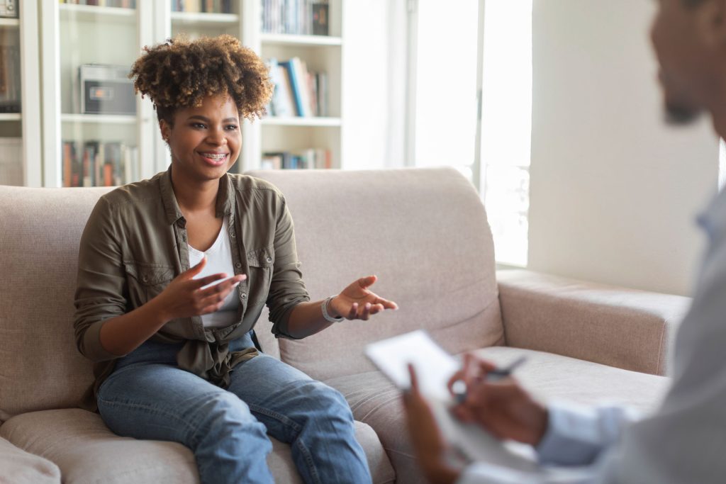 Happy african-american woman speaking with a therapist.