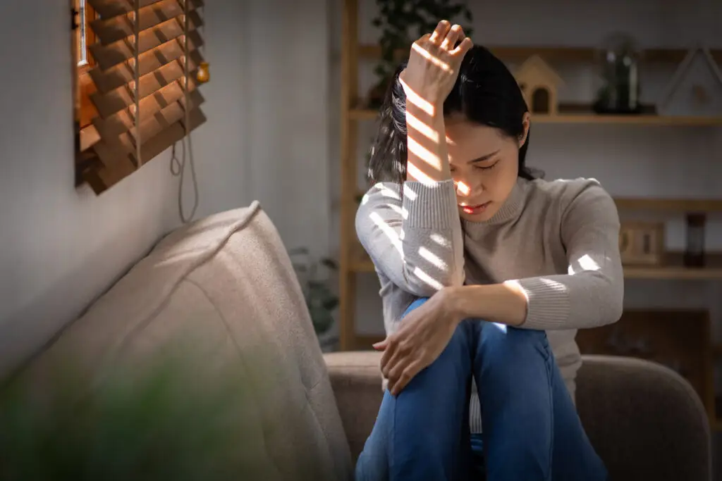 Sad woman seated on couch.