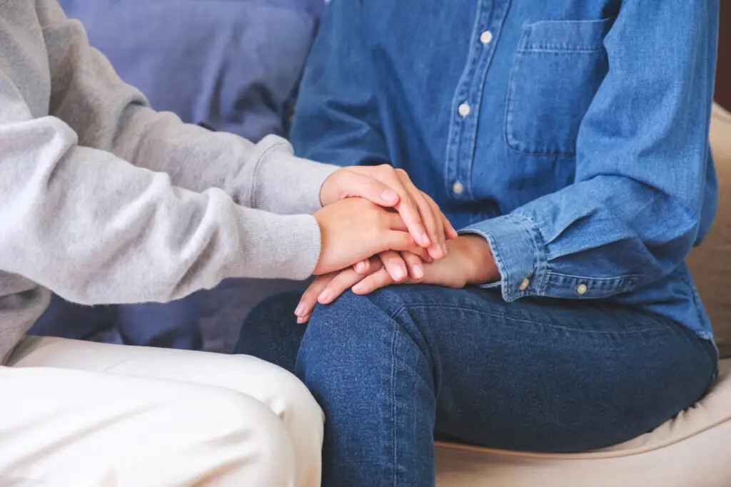 hands comforting another person.