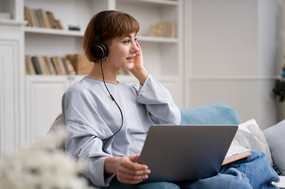 young woman wearing headphones and using a laptop for an online therapy session